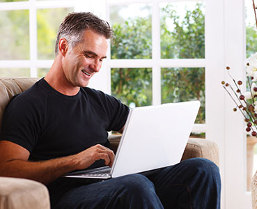 Photo of a man on a computer. Links to Gifts of Cash, Checks, and Credit Cards